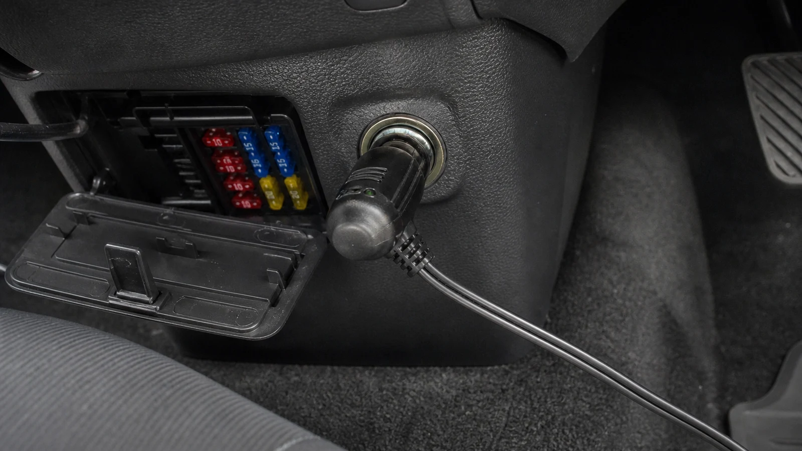 Car 12V accessory socket beside an open fuse box after using a tyre inflator