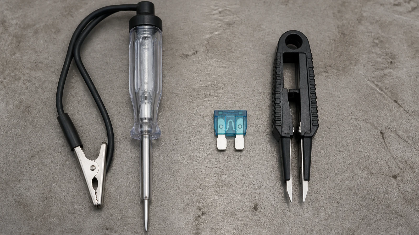 Comparison of a basic automotive test light and a combined blade fuse tester-puller on a workbench